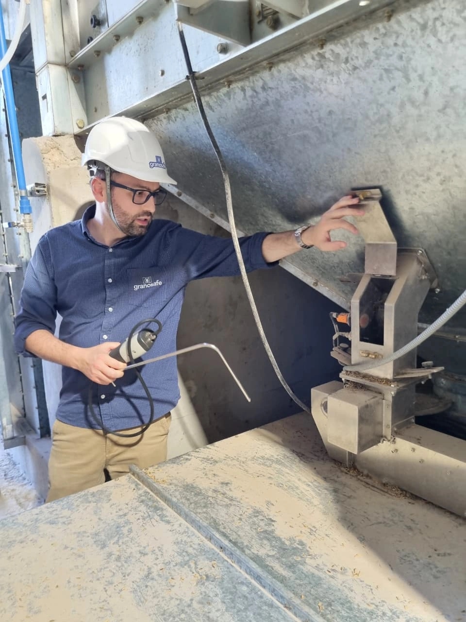 Instrutor da Grano Safe com capacete utilizando termômetro digital para medir a temperatura de grãos armazenados