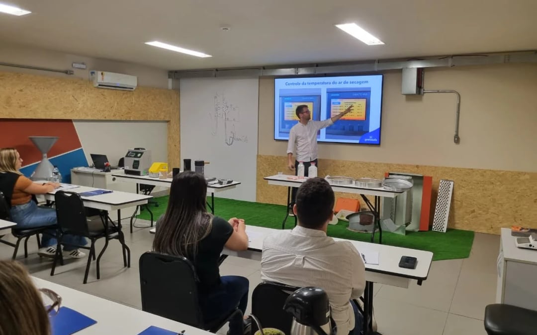 Instrutor apresentando slide sobre controle de temperatura do ar de secagem para turma em sala técnica de treinamento